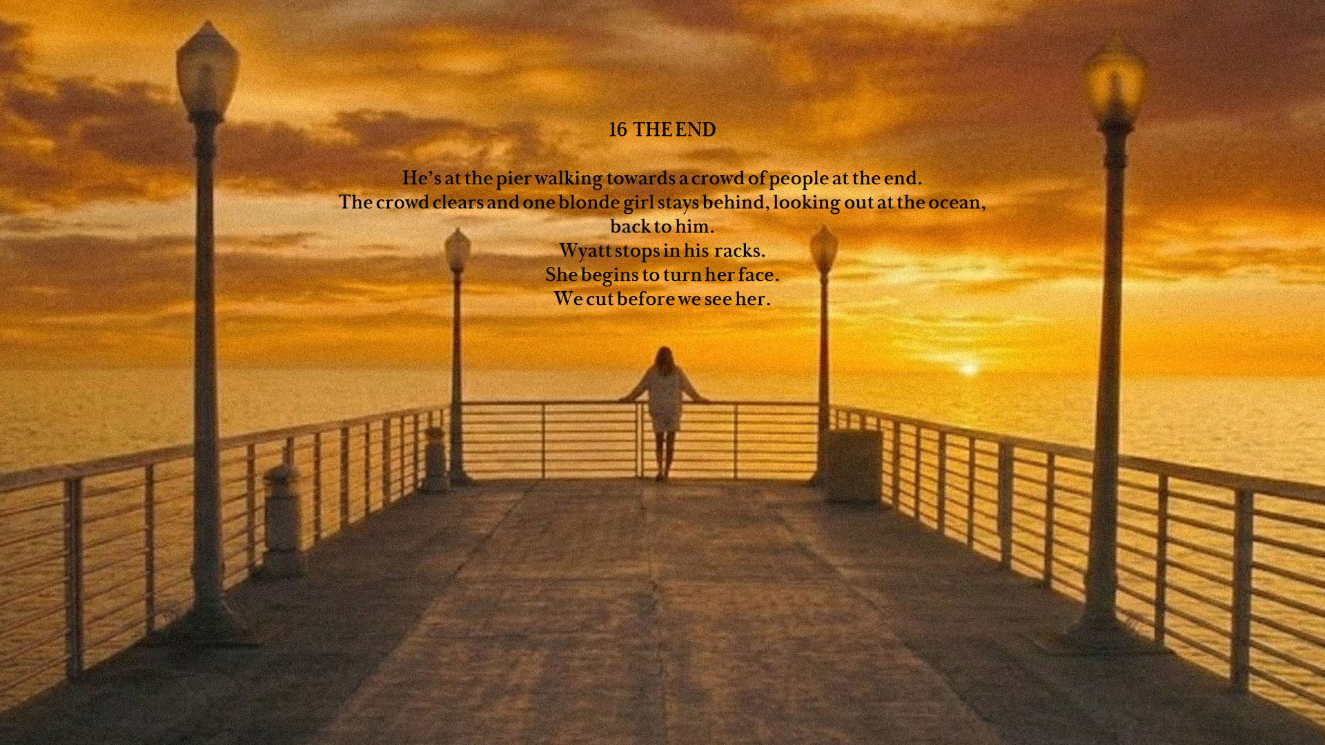 A person standing at the end of a pier looking out at the ocean during a golden sunset.