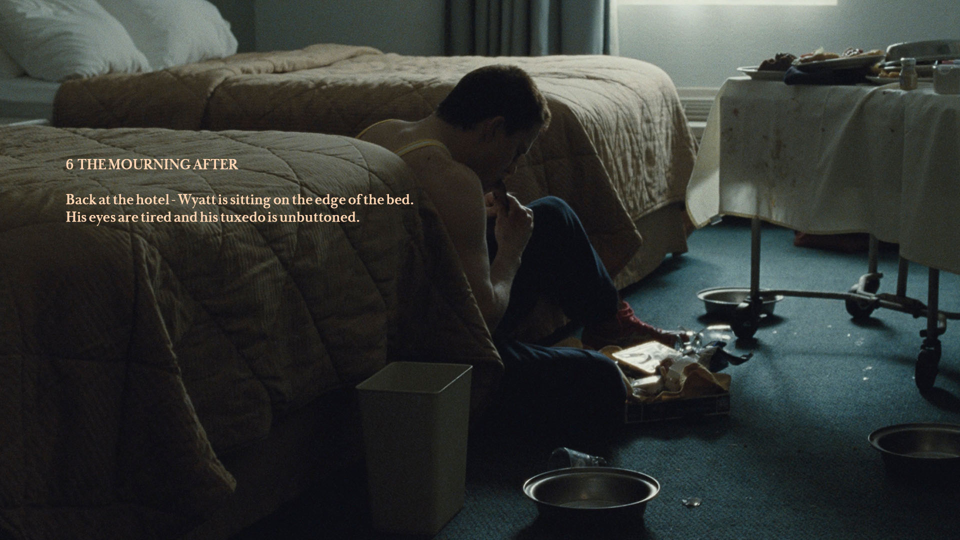 A man sitting on the edge of a hotel bed.
